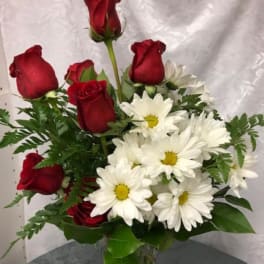 Bouquet of red roses and white daisies in a clear glass vase
