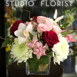 Bouquet of red and pink roses with white orchids in a glass vase