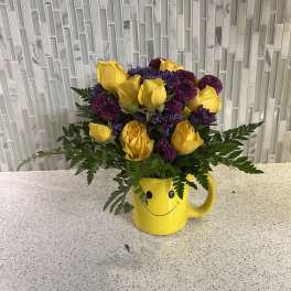 Yellow roses and purple mums in a yellow smiley-face mug