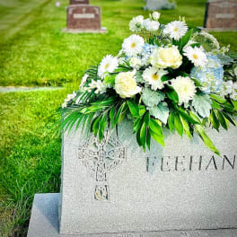 White and pale blue floral arrangement on a gravestone