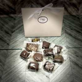 Box of assorted chocolates with a ribbon-tied gift bag