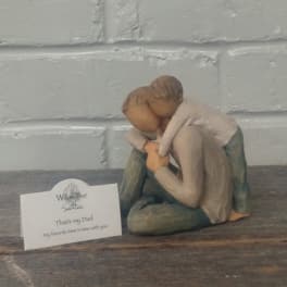 Small figurine of two people hugging beside a sympathy card