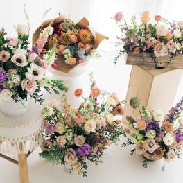 Assorted pastel flower arrangements in vases and boxes