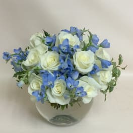 White roses and blue flowers in a clear glass vase
