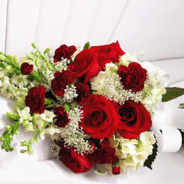 Red roses and white flowers arranged in a hand-tied bouquet