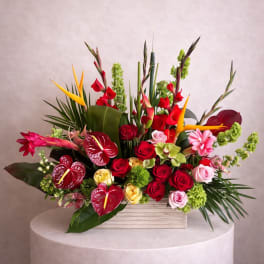 Tropical bouquet with red roses, anthuriums, and bird-of-paradise in a wooden box