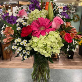 Mixed bouquet in a glass vase with pink, purple, green, and white flowers
