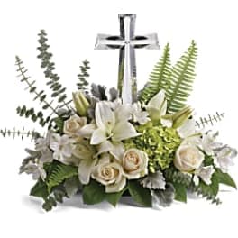 White lilies and roses arranged around a silver cross