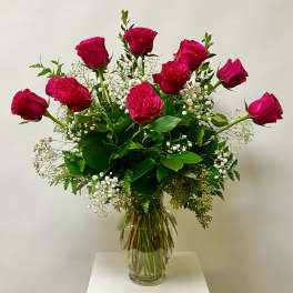 Pink roses arranged in a clear glass vase with white baby's breath