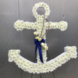 Anchor-shaped standing spray of white flowers with blue ribbon and rope accent.