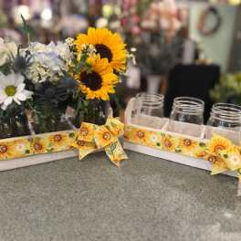 Sunflower and daisy arrangements in mason jars on a tray with sunflower ribbon