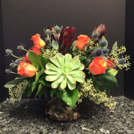 Orange roses and succulents arranged in a dark glass vase