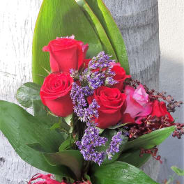 Bouquet of red roses with purple filler and broad green leaves