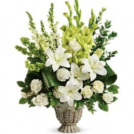 White lilies and green flowers arranged in a decorative urn