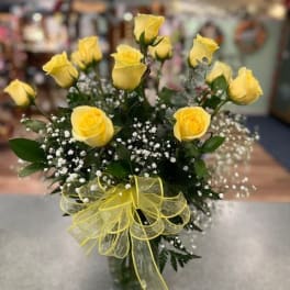Yellow roses in a glass vase with baby's breath and a yellow ribbon bow