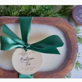 Soy candle in a wooden tray with a green ribbon and pine sprigs