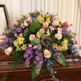 Large pastel floral spray on a wooden casket