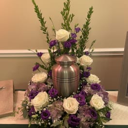 White and purple roses arranged around a silver urn