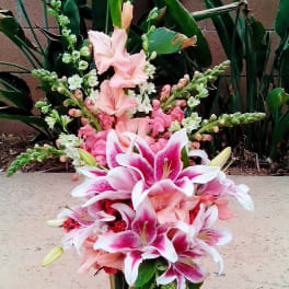 Pink and white lilies arranged in a tall gold vase