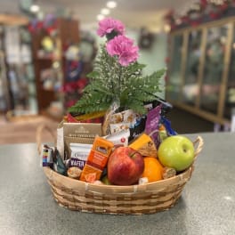 Gift basket with fruit, chocolates, and pink flowers in a wicker basket