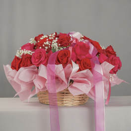 Basket of red and pink roses with baby’s breath and pink ribbons