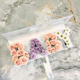 Floral arrangement spelling "A" with peach and lavender roses and white daisies