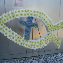 Fish-shaped floral tribute with white and blue flowers on a stand
