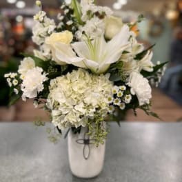 White floral arrangement in a tall vase with lilies and hydrangeas