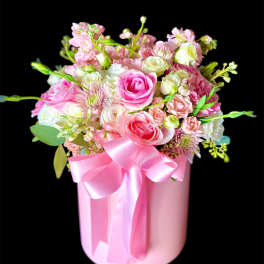 Pink and white mixed flower arrangement in a pink box with a ribbon