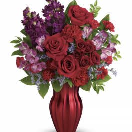 Red roses and purple flowers arranged in a red vase
