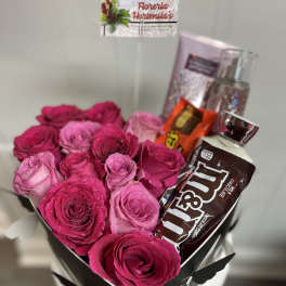 Pink and magenta roses in a black gift box with chocolates and perfume