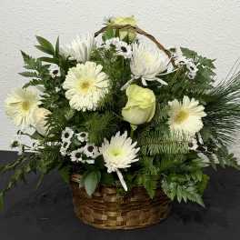 White flowers arranged in a wicker basket with greenery