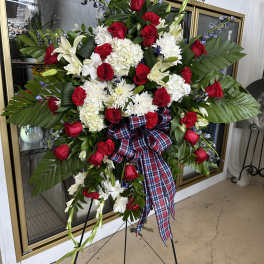 Standing floral spray with red roses, white lilies, and a plaid ribbon