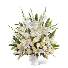 Tall white arrangement with lilies, roses, and gladiolus in a white pedestal vase