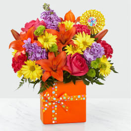 Bright mixed bouquet in an orange gift box with a birthday rosette