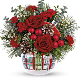 Red roses and holiday accents in a decorated glass vase