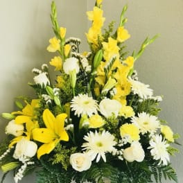 Tall yellow and white flower arrangement with lilies, roses, and daisies in a white woven basket