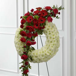 Standing white floral wreath with cascading red roses, gerberas, and carnations