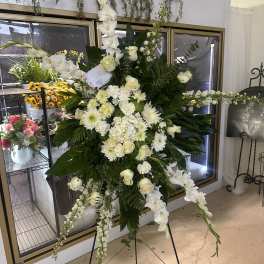 Large white funeral spray on a stand with cascading flowers
