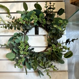 Green eucalyptus wreath with small buds on a white slat wall
