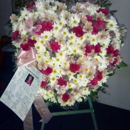 Heart-shaped floral spray with white daisies and pink roses on an easel