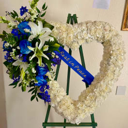 Heart-shaped white floral wreath with blue and white bouquet and a "Rest in Peace" ribbon