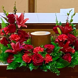 Red floral altar arrangement with a central candle holder