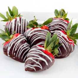 Chocolate-covered strawberries with white drizzle on a white surface