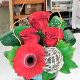 Red roses and a gerbera daisy in a decorative basket arrangement