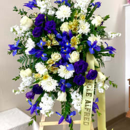 Standing floral spray with blue, white, and purple flowers on an easel