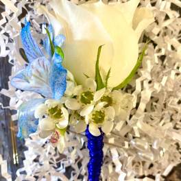 White rose boutonniere with blue accent flowers and white filler
