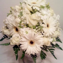 White gerbera daisies and roses arranged in a silver vase