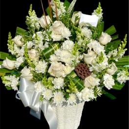 White roses and chrysanthemums in a white basket with a silver ribbon
