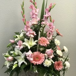 Tall pink and white flower arrangement with lilies, roses, and gerberas in a white wicker basket